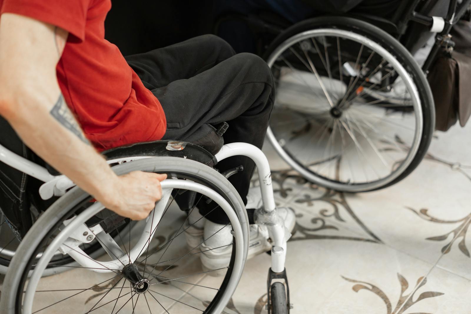 Close-up of person in wheelchair wearing red shirt, indoors.