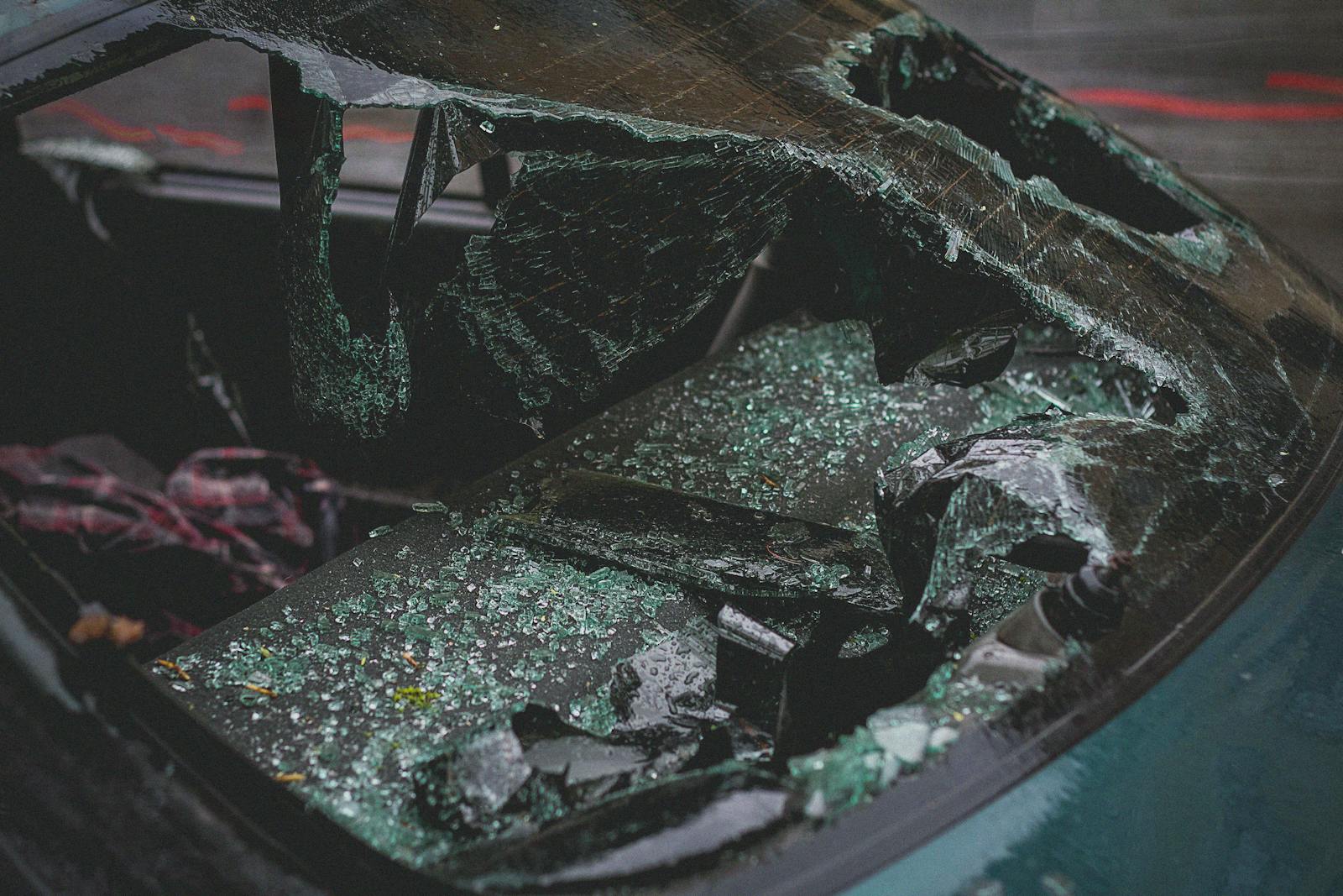 Detailed view of shattered car windshield after accident, emphasizing damage and broken glass.