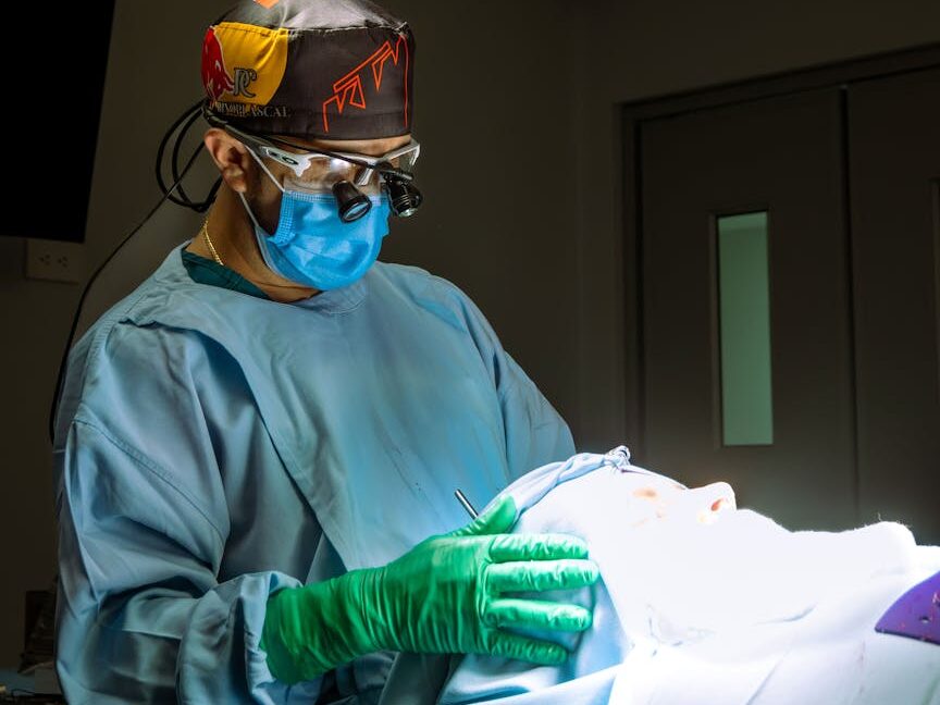 Surgeon in protective gear conducting a medical procedure in an operating room.