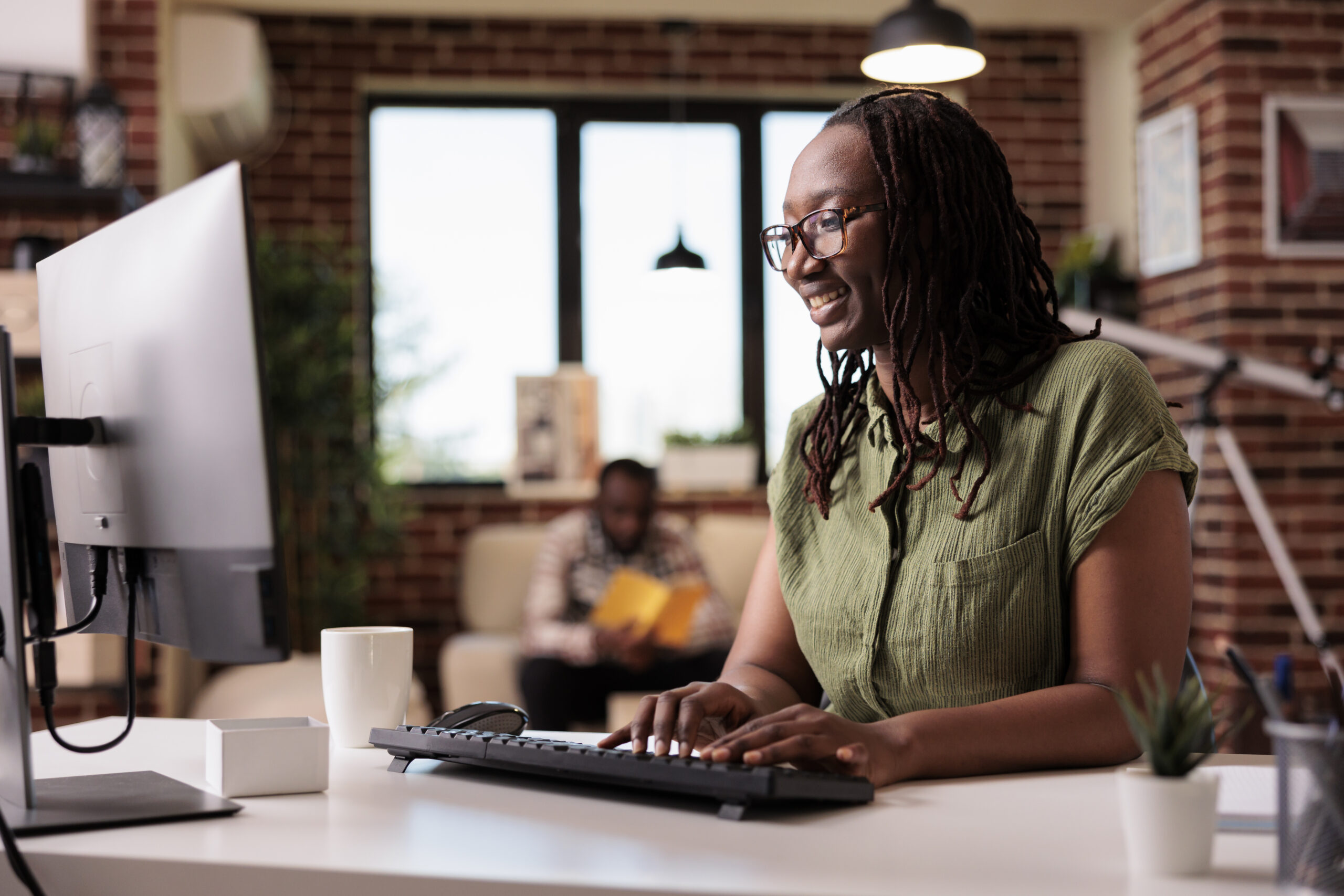 african american freelancer working remote typing looking computer screen while boyfriend is relaxing smiling programmer using pc chat with friends while roommate is reading book scaled