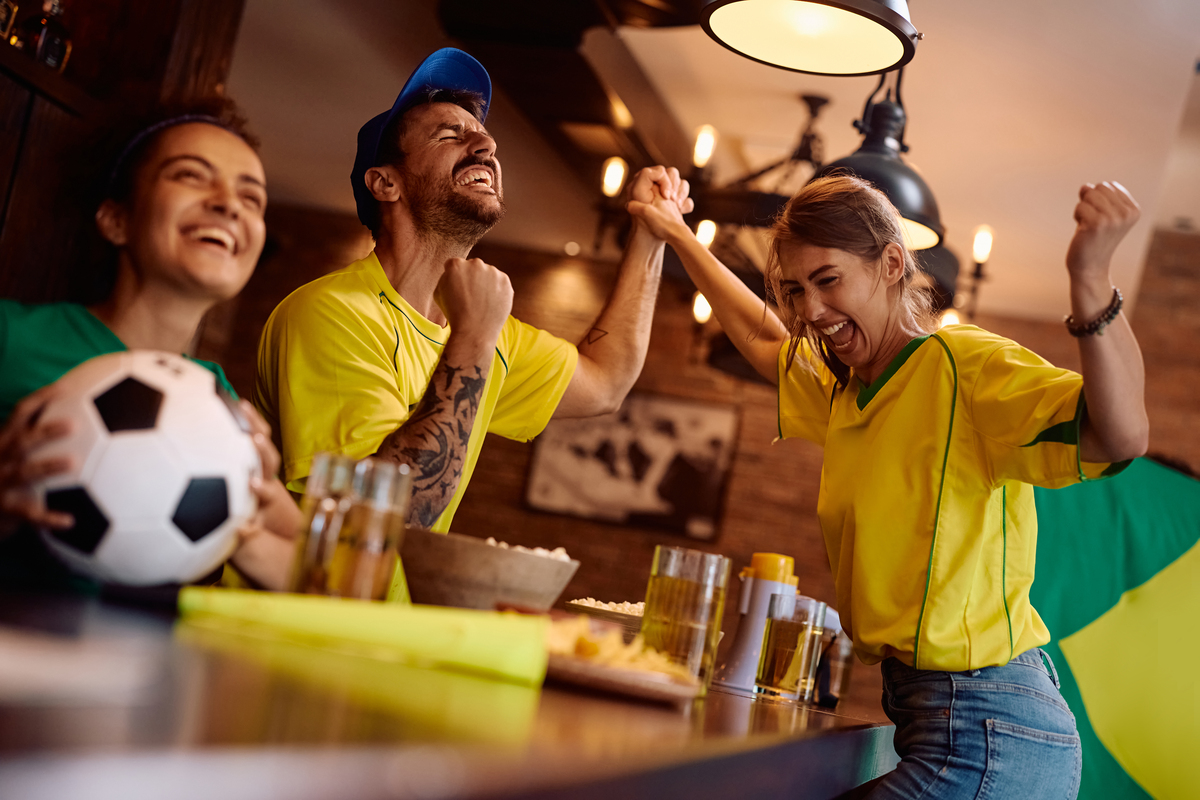 Comércio capixaba deve movimentar R$ 56,9 bilhões durante a Copa do Mundo 5 Torcedores do Brasil vendo jogo em bar Envato.jpg 1